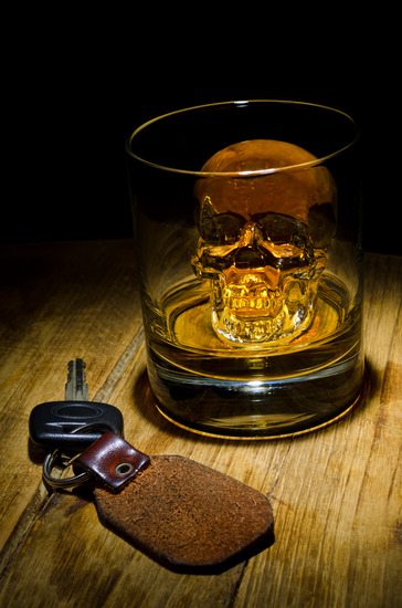 A glass of whiskey with a skull ice cube with car keys.