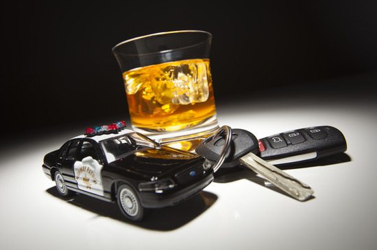 Highway Patrol Police Car Next to Alcoholic Drink and Keys Under Spot Light.
