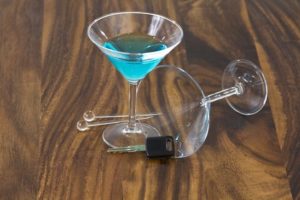 Mixed drinks with stir sticks and car key on wooden table